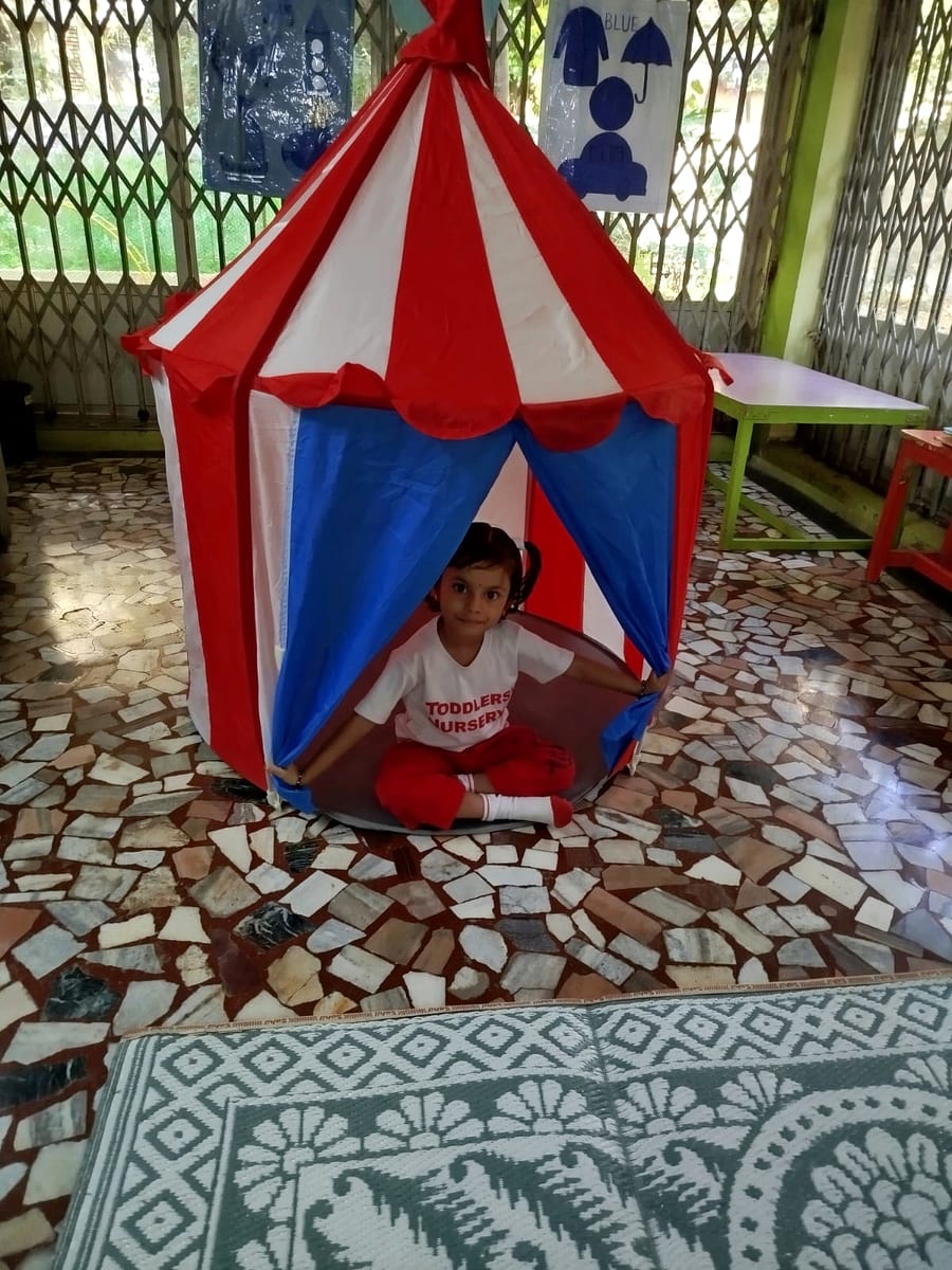 Children smiling inside a colorful indoor play tent