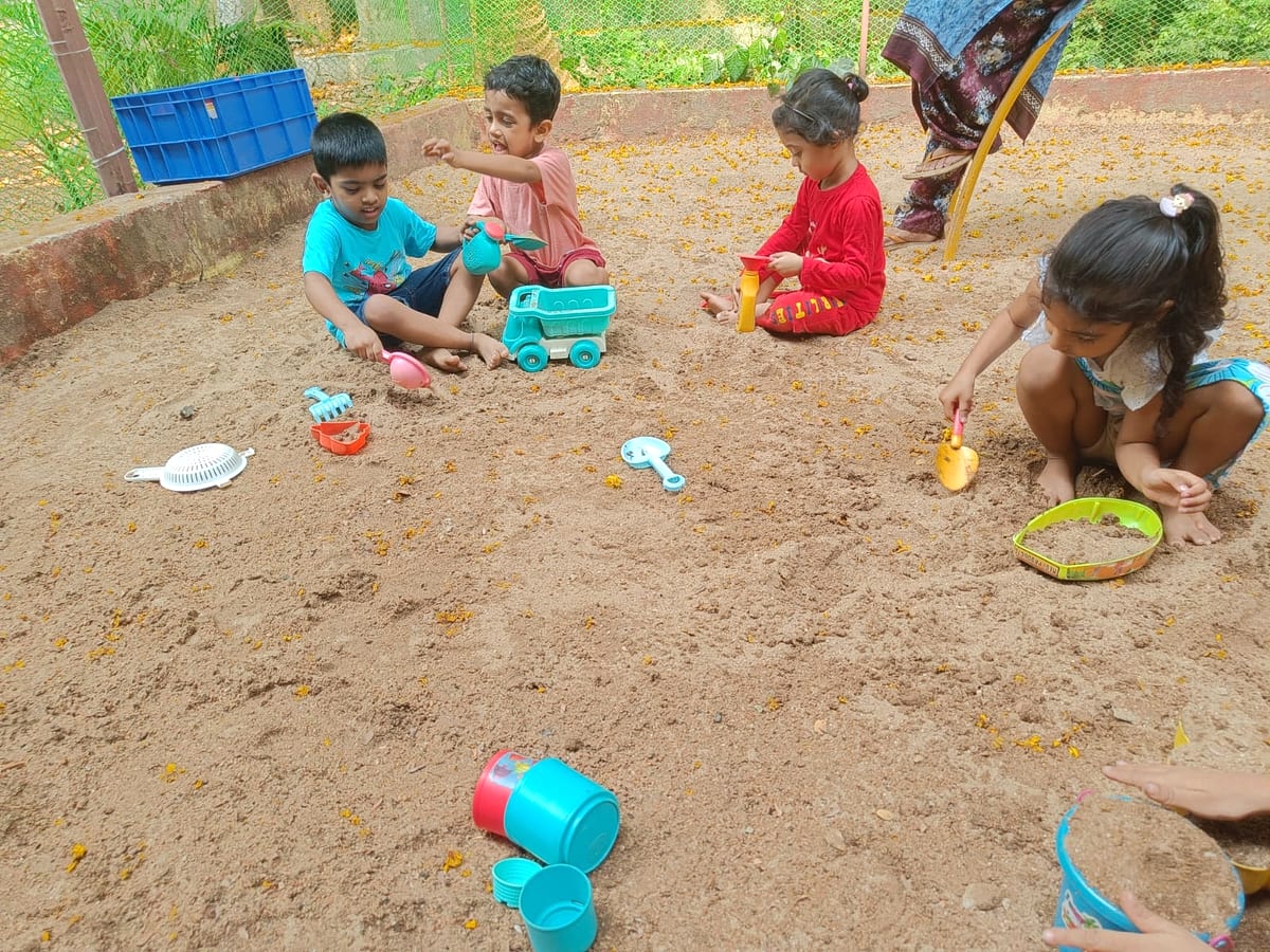 Children playing together in the sandbox during outdoor play time